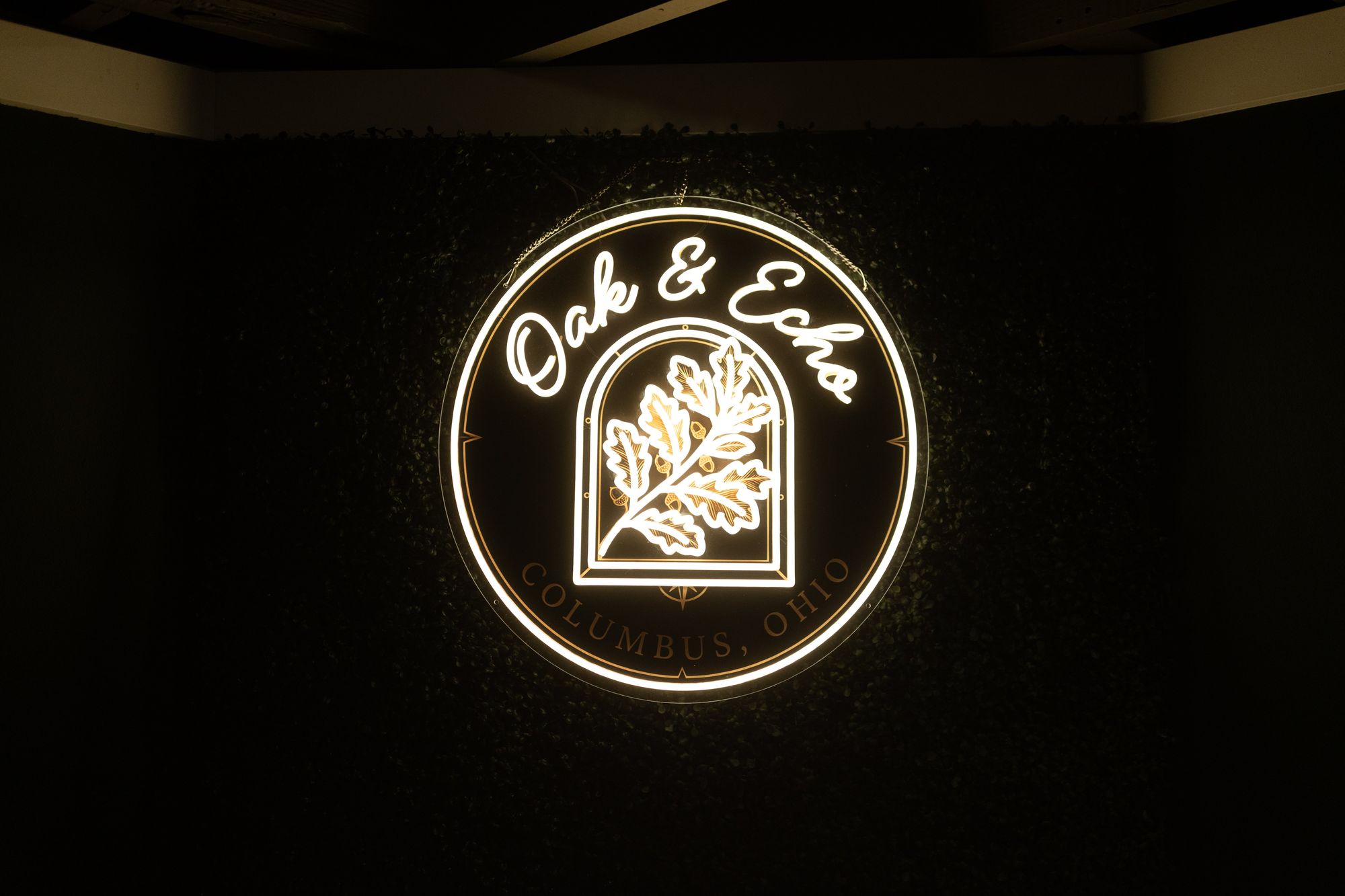 The Oak & Echo sign glowing on a dark green wall